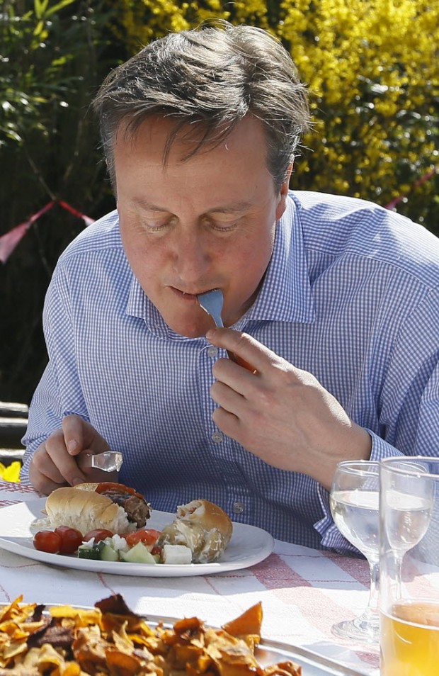 Cameron saboreando um hot dog com talheres. Crédito:  AFP PHOTO/POOL